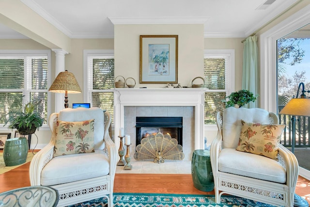 living area with a tile fireplace, ornamental molding, and hardwood / wood-style flooring