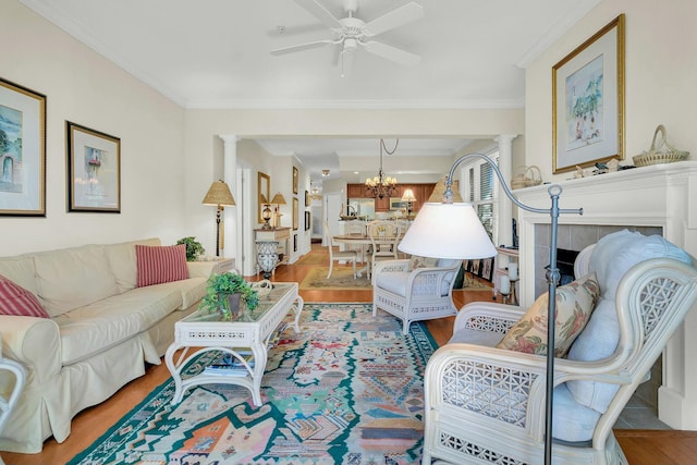 living room featuring ceiling fan with notable chandelier, light hardwood / wood-style flooring, ornamental molding, and ornate columns