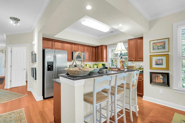 kitchen with a breakfast bar, ornamental molding, a center island, light hardwood / wood-style floors, and stainless steel refrigerator with ice dispenser