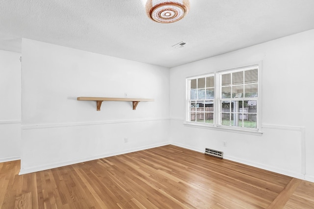 empty room with wood-type flooring and a textured ceiling