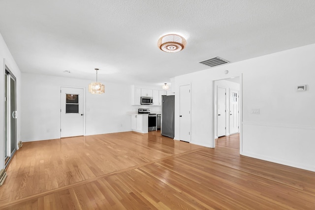 unfurnished living room featuring light hardwood / wood-style floors and a textured ceiling