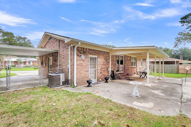 rear view of property with a lawn, central air condition unit, and a patio area