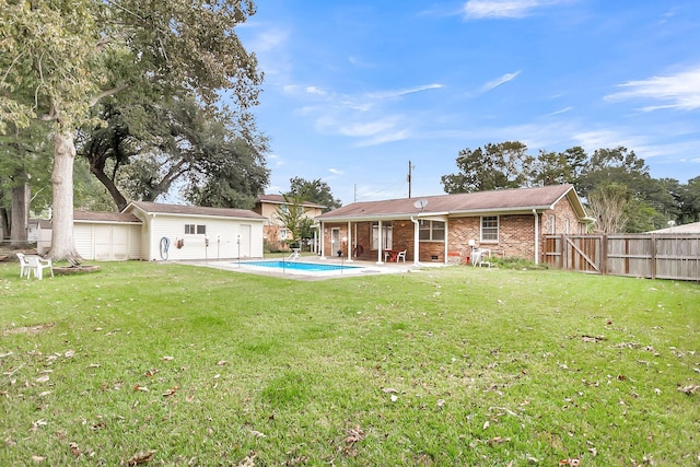 back of house with an outbuilding, a yard, a fenced in pool, and a patio area