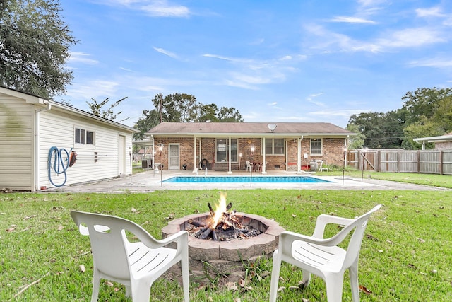 rear view of property with a lawn, a patio area, and a fire pit