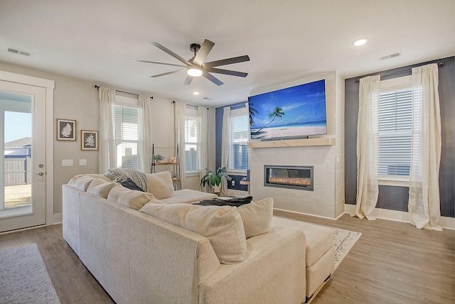 living room featuring hardwood / wood-style flooring, a wealth of natural light, a large fireplace, and ceiling fan