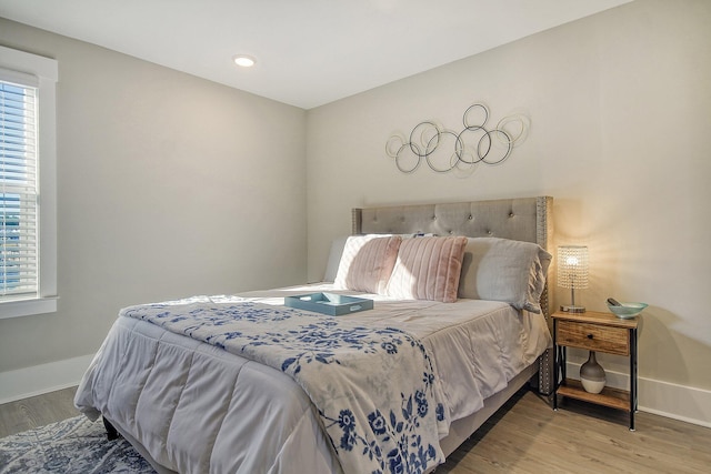 bedroom with multiple windows and hardwood / wood-style floors