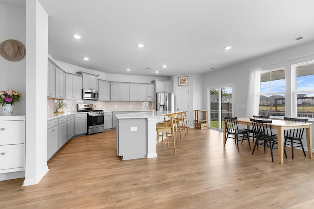 211 Squire Pope Rd, Summerville, SC 29486 - kitchen with stainless steel appliances, gray cabinetry, a breakfast bar area, light countertops, and tasteful backsplash