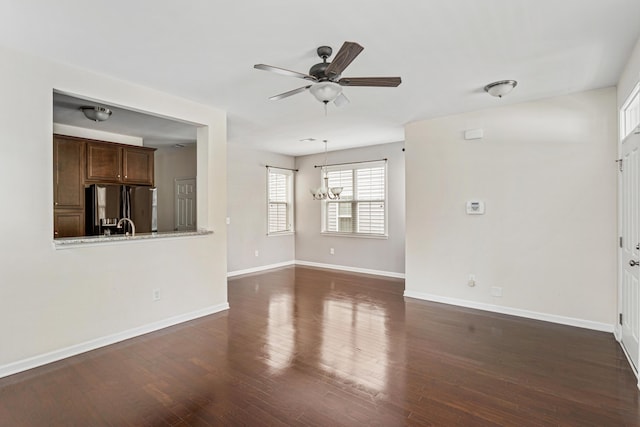 unfurnished living room featuring ceiling fan with notable chandelier and dark hardwood / wood-style flooring