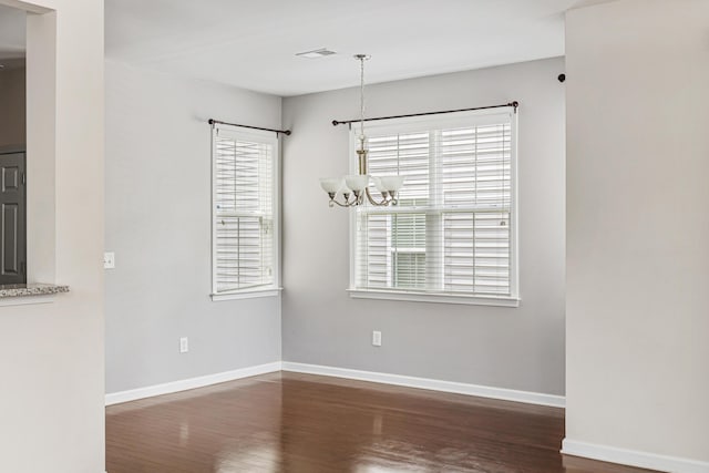 unfurnished dining area featuring an inviting chandelier and dark hardwood / wood-style flooring