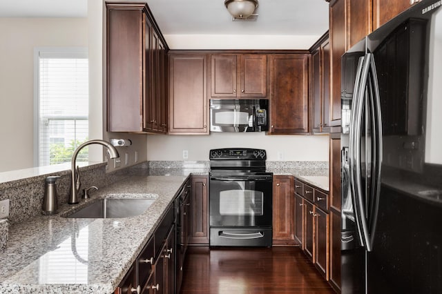 kitchen with dark hardwood / wood-style floors, sink, black appliances, light stone countertops, and dark brown cabinets