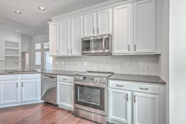 kitchen featuring dark hardwood / wood-style floors, sink, white cabinets, dark stone counters, and stainless steel appliances