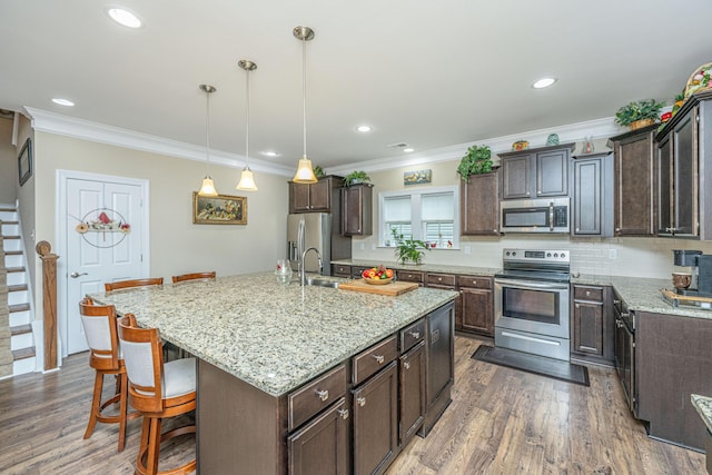 220 Brutus Ln, Summerville, SC 29485 - kitchen with stainless steel appliances, a kitchen bar, dark brown cabinets, a center island with sink, and dark wood finished floors