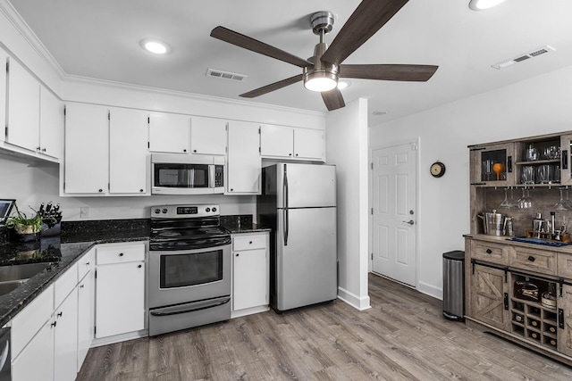 kitchen featuring ceiling fan, dark stone countertops, stainless steel appliances, light hardwood / wood-style floors, and white cabinets