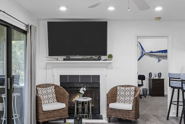 sitting room with hardwood / wood-style flooring, a tile fireplace, and ceiling fan