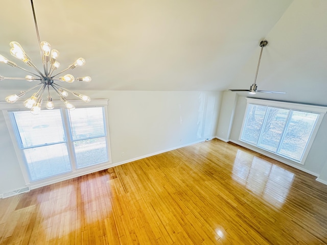 unfurnished living room with a notable chandelier, a healthy amount of sunlight, light wood-style floors, and vaulted ceiling