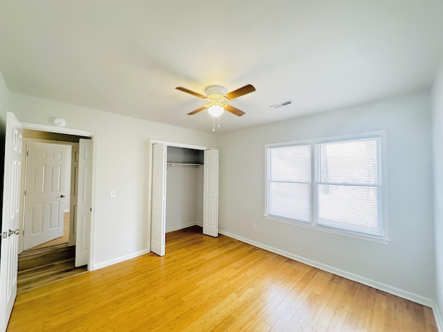 unfurnished bedroom featuring a ceiling fan, visible vents, baseboards, light wood-style flooring, and a closet