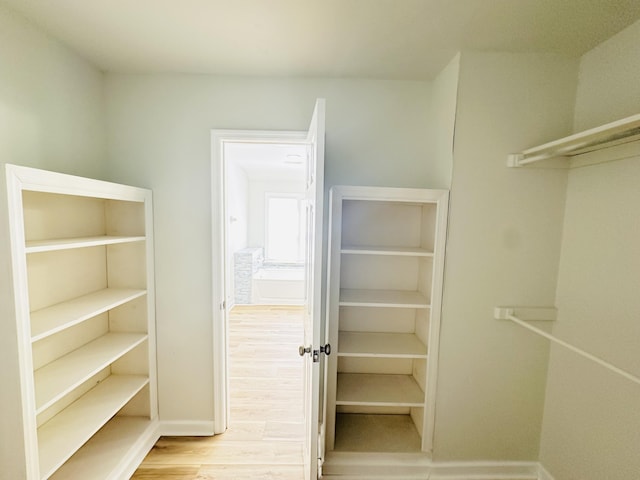 walk in closet with wood finished floors