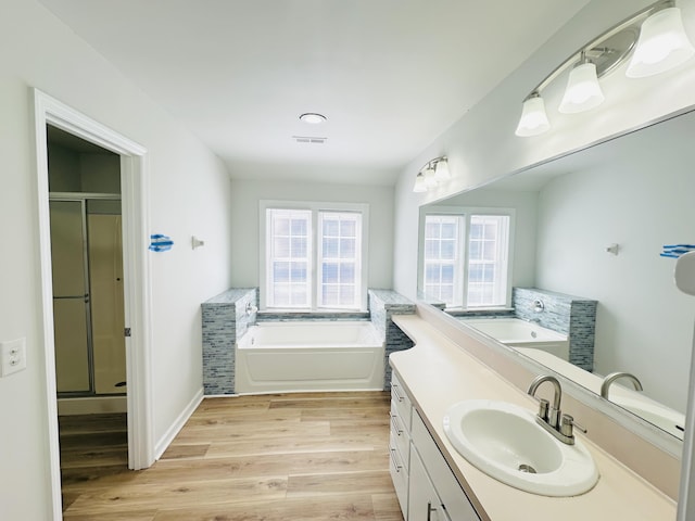 bathroom featuring visible vents, wood finished floors, a shower stall, a bath, and vanity