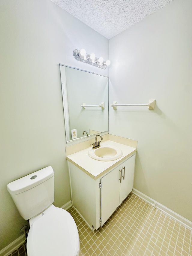 half bathroom featuring baseboards, a textured ceiling, vanity, and toilet