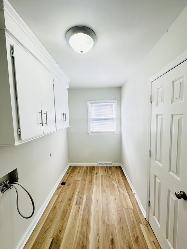 clothes washing area featuring visible vents, cabinet space, light wood-style floors, baseboards, and hookup for a washing machine