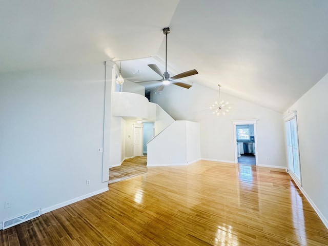 unfurnished living room with light wood finished floors, visible vents, baseboards, ceiling fan with notable chandelier, and high vaulted ceiling