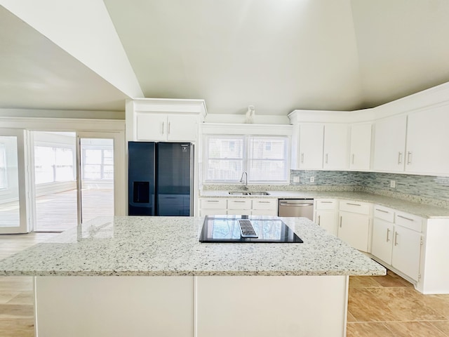 kitchen featuring a kitchen island, a sink, decorative backsplash, appliances with stainless steel finishes, and white cabinetry