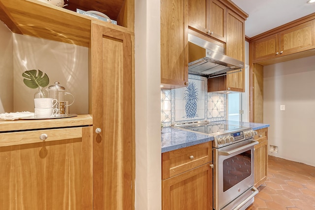 1 King Street 209 & 210, Charleston, SC 29401 - kitchen featuring stainless steel range with electric cooktop, under cabinet range hood, backsplash, light tile patterned floors, and brown cabinetry