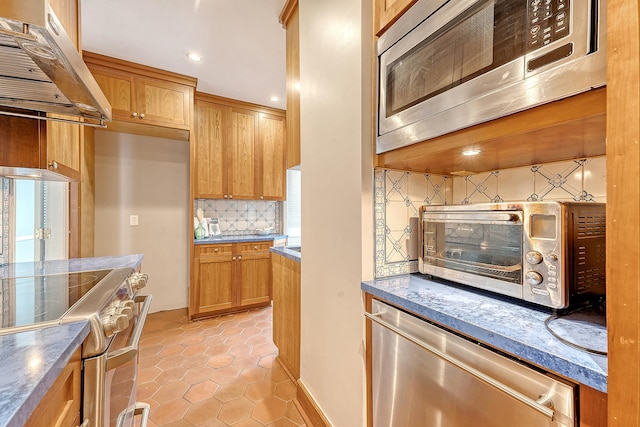 1 King Street 209 & 210, Charleston, SC 29401 - kitchen with under cabinet range hood, appliances with stainless steel finishes, backsplash, light tile patterned flooring, and recessed lighting