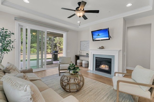 living room featuring a fireplace with flush hearth, crown molding, wood finished floors, and recessed lighting