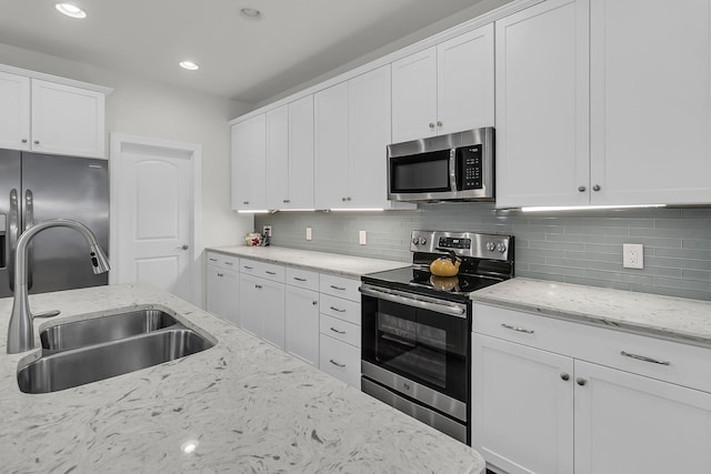kitchen with white cabinets, recessed lighting, appliances with stainless steel finishes, a sink, and backsplash