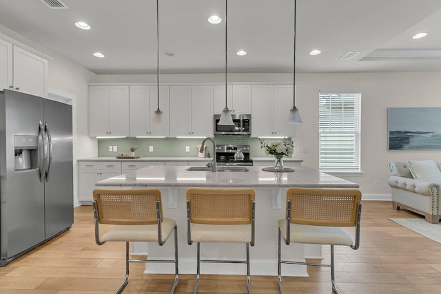 kitchen with white cabinets, a sink, appliances with stainless steel finishes, and light wood-style flooring