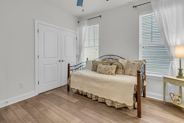 bedroom with a closet, baseboards, ceiling fan, and wood finished floors