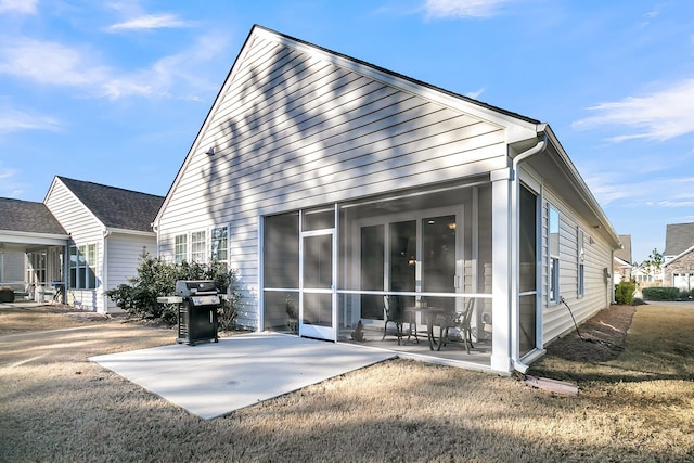 rear view of property featuring a sunroom and a patio area