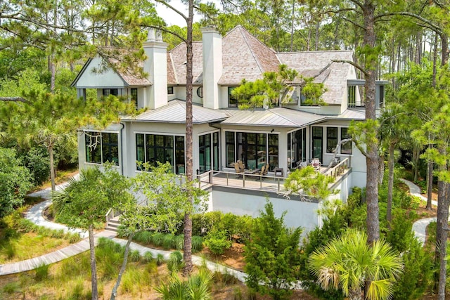 79 Trailing Vine Way, Kiawah Island, SC 29455 - back of property featuring a sunroom, a standing seam roof, a chimney, stucco siding, and a metal roof
