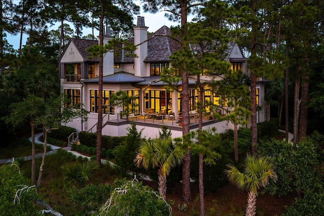 79 Trailing Vine Way, Kiawah Island, SC 29455 - back of house featuring stucco siding, a chimney, a standing seam roof, a metal roof, and a balcony
