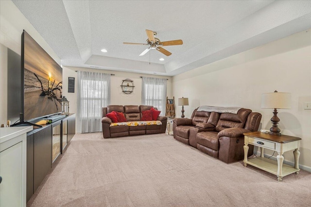 living room with recessed lighting, a tray ceiling, a ceiling fan, light carpet, and a textured ceiling