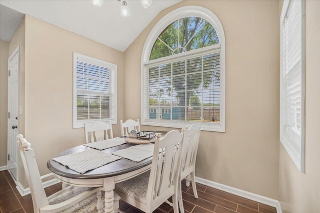 dining space with wood tiled floor, vaulted ceiling, and baseboards