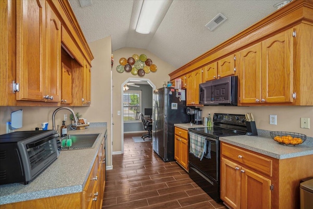 kitchen with a sink, appliances with stainless steel finishes, baseboards, a toaster, and vaulted ceiling