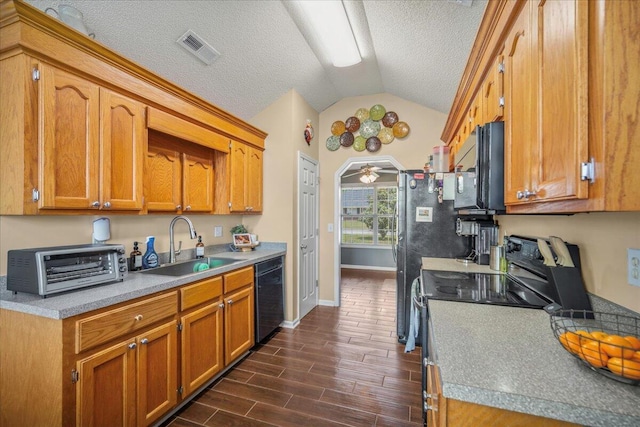 kitchen with vaulted ceiling, black appliances, a sink, visible vents, and dark wood-type flooring