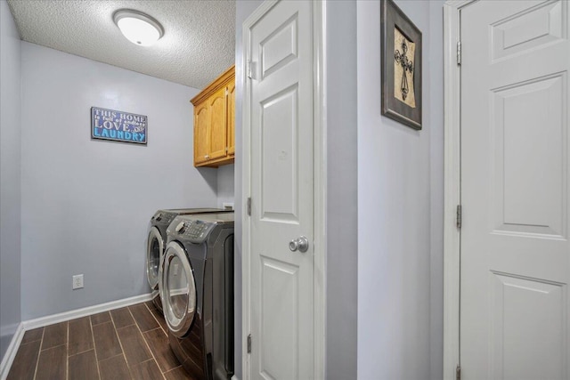clothes washing area with cabinet space, washing machine and clothes dryer, baseboards, wood finish floors, and a textured ceiling
