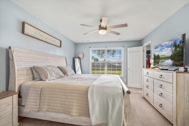 bedroom featuring a textured ceiling, ceiling fan, and light carpet