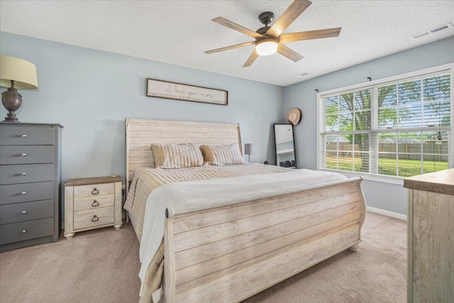 bedroom featuring a textured ceiling, visible vents, and light colored carpet