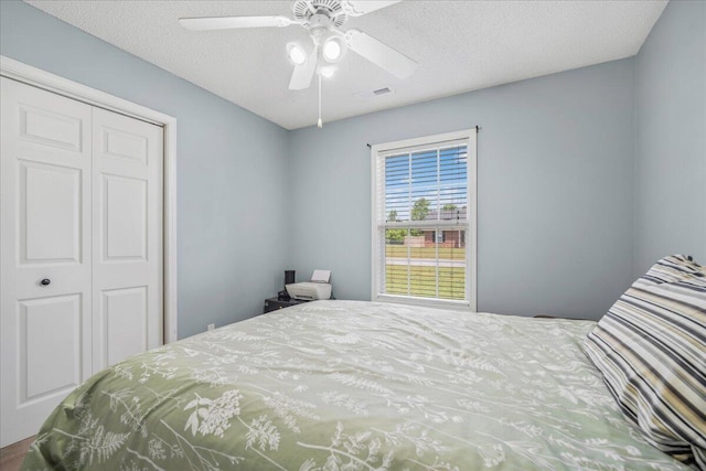 bedroom with visible vents, a ceiling fan, a textured ceiling, and a closet