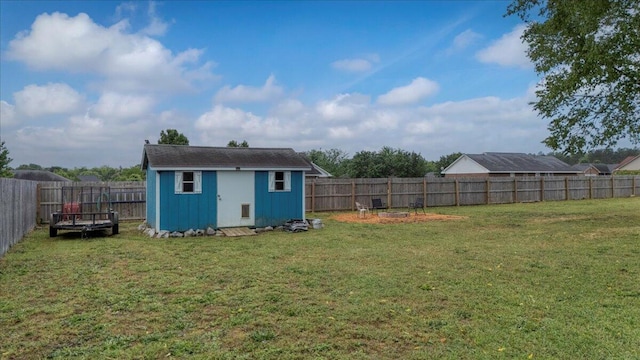 rear view of property with an outbuilding, a lawn, a storage unit, and a fenced backyard