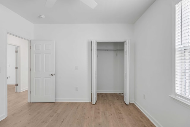 unfurnished bedroom featuring ceiling fan, light hardwood / wood-style floors, and a closet