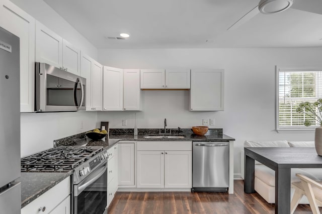 kitchen with dark stone countertops, appliances with stainless steel finishes, sink, and white cabinets