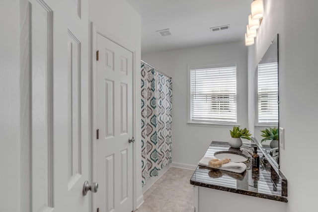 bathroom with walk in shower, vanity, and tile patterned flooring