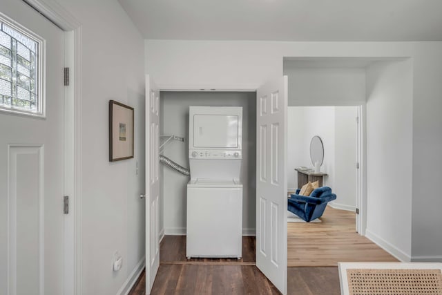 laundry area with stacked washer / drying machine and dark hardwood / wood-style floors