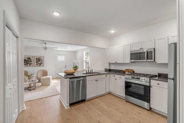 kitchen featuring white cabinetry, appliances with stainless steel finishes, light hardwood / wood-style flooring, and kitchen peninsula