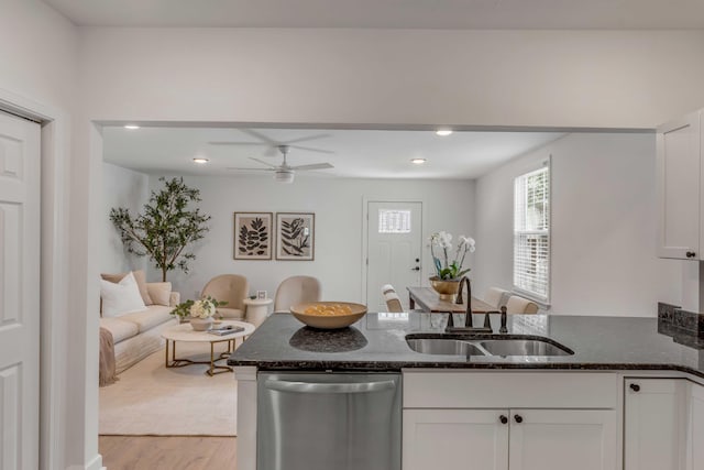 kitchen featuring sink, white cabinetry, stainless steel dishwasher, dark stone counters, and light hardwood / wood-style floors